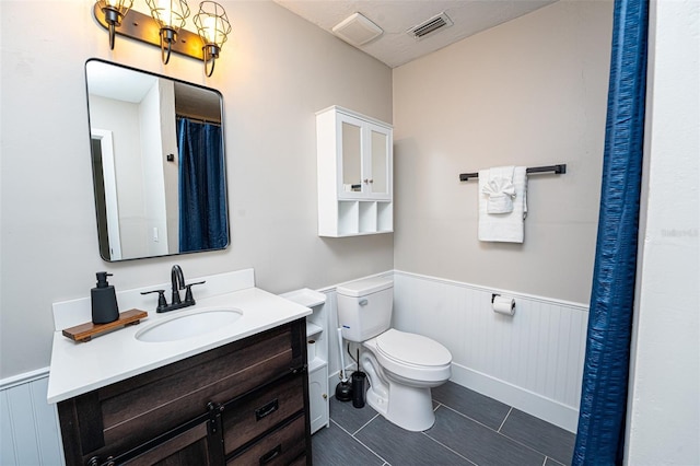 full bath with toilet, wainscoting, vanity, and visible vents