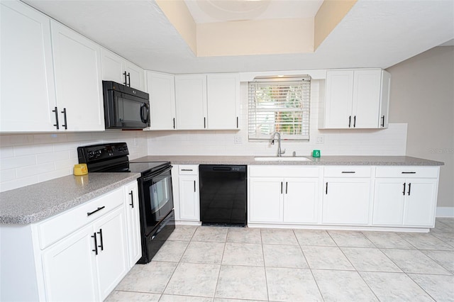 kitchen featuring a tray ceiling, decorative backsplash, white cabinets, a sink, and black appliances