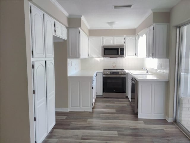 kitchen featuring backsplash, stainless steel appliances, sink, hardwood / wood-style flooring, and white cabinets