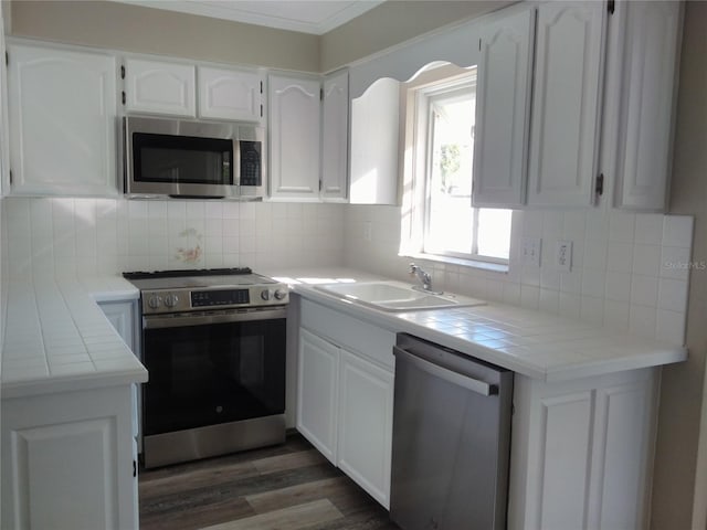 kitchen with sink, stainless steel appliances, backsplash, tile countertops, and white cabinets