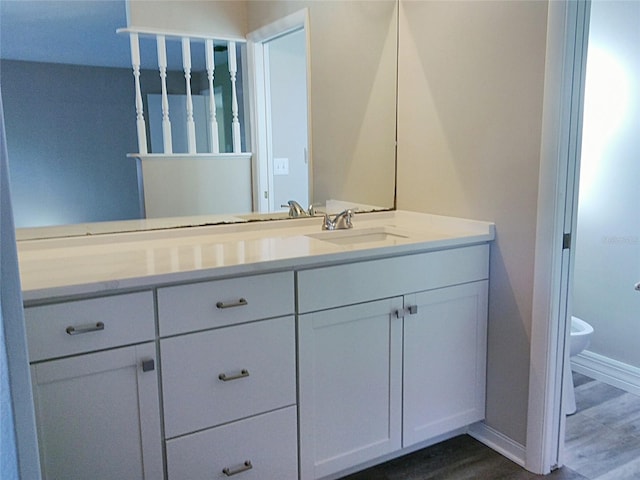 bathroom with hardwood / wood-style floors, vanity, and toilet