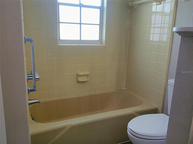 bathroom with toilet and tiled shower / bath