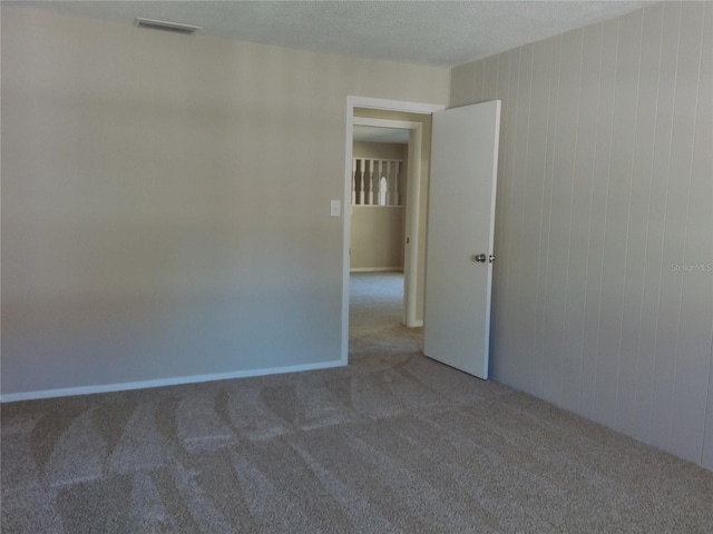 carpeted empty room with a textured ceiling