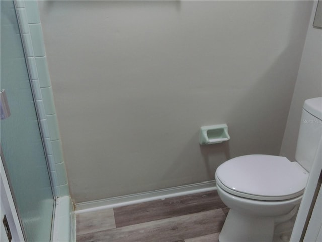 bathroom featuring hardwood / wood-style floors, toilet, and a shower with door