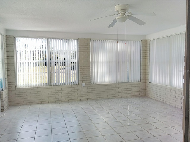 tiled empty room featuring a wealth of natural light and ceiling fan