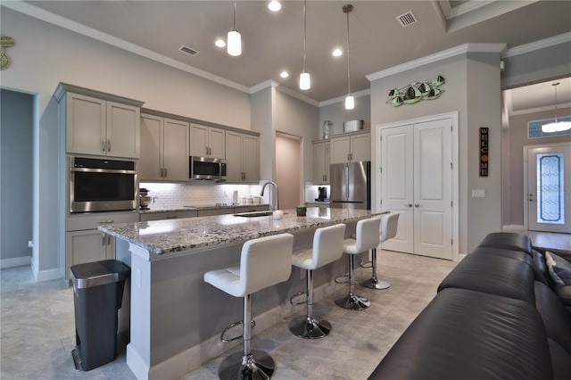 kitchen featuring appliances with stainless steel finishes, a breakfast bar area, pendant lighting, and an island with sink