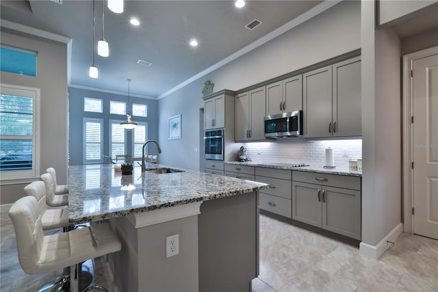 kitchen featuring gray cabinetry, sink, decorative light fixtures, a center island with sink, and appliances with stainless steel finishes