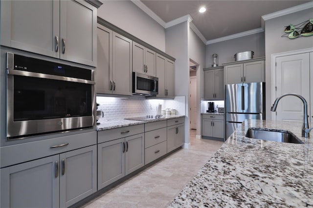 kitchen with backsplash, sink, gray cabinets, light stone counters, and stainless steel appliances