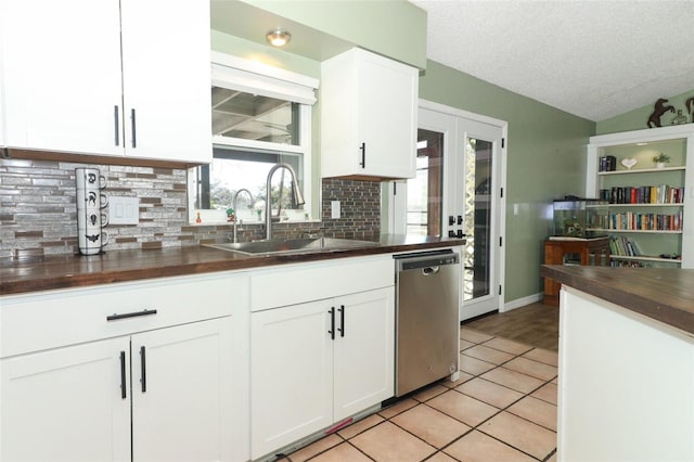 kitchen with lofted ceiling, a sink, white cabinetry, backsplash, and dishwasher