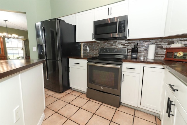 kitchen featuring stainless steel appliances, tasteful backsplash, dark countertops, and white cabinetry