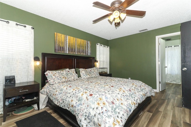 bedroom with baseboards, visible vents, ceiling fan, wood finished floors, and a textured ceiling