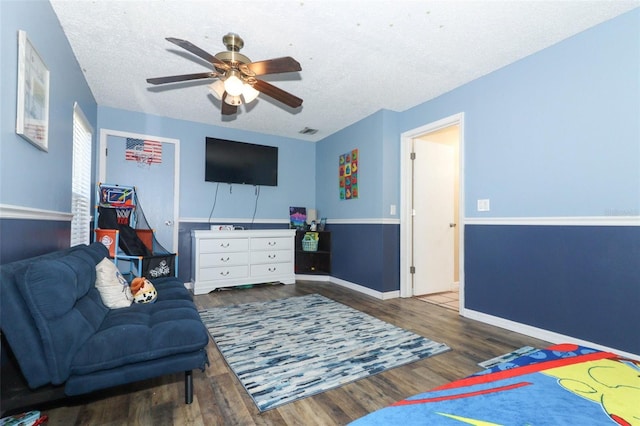 interior space featuring ceiling fan, baseboards, a textured ceiling, and wood finished floors