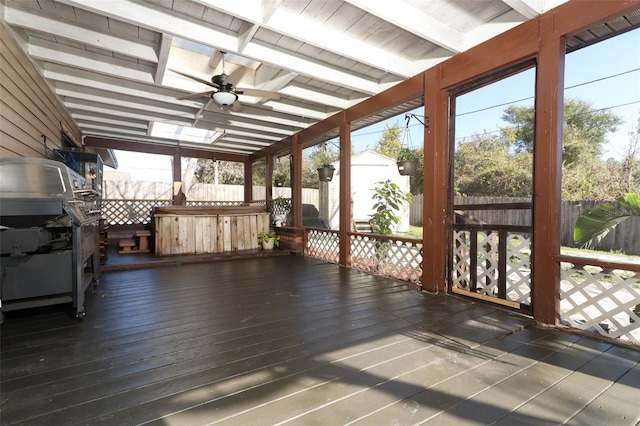 unfurnished sunroom featuring ceiling fan, beamed ceiling, and plenty of natural light