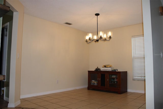 unfurnished dining area with a notable chandelier, light tile patterned floors, visible vents, and baseboards