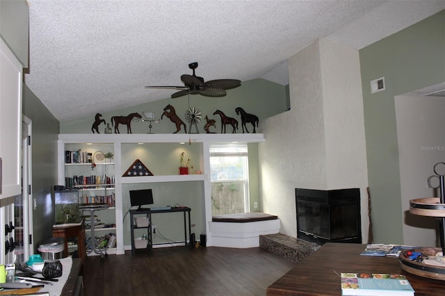 living room featuring lofted ceiling, visible vents, a ceiling fan, a glass covered fireplace, and wood finished floors