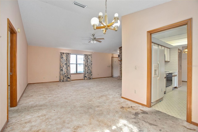 carpeted spare room featuring ceiling fan with notable chandelier and vaulted ceiling