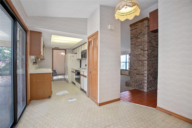 corridor with a notable chandelier, sink, and a textured ceiling