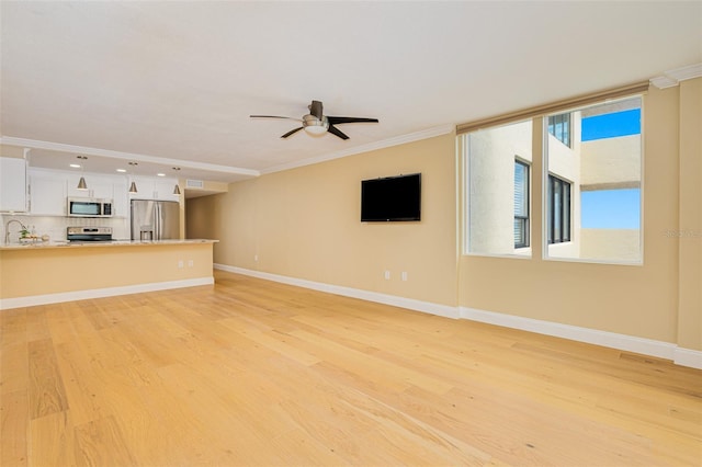 unfurnished living room with ceiling fan, crown molding, light hardwood / wood-style flooring, and sink