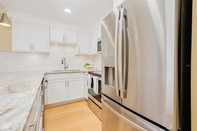 kitchen with light hardwood / wood-style floors, stainless steel appliances, white cabinets, light stone counters, and sink