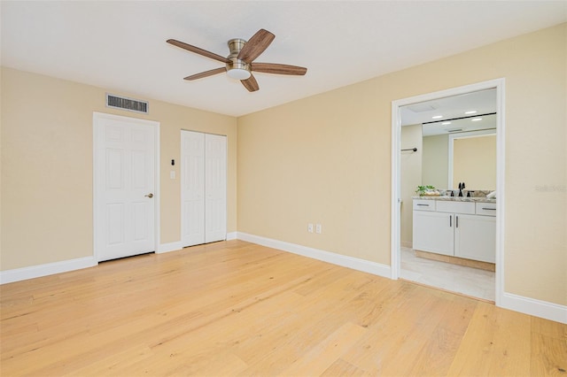 unfurnished bedroom with ensuite bathroom, two closets, ceiling fan, light hardwood / wood-style flooring, and sink