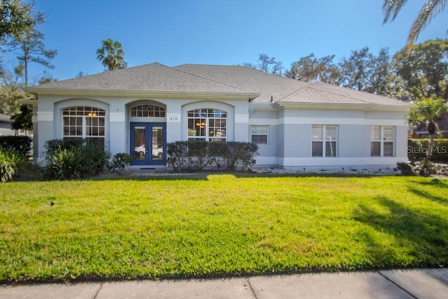 view of front of property with stucco siding, a front lawn, and french doors