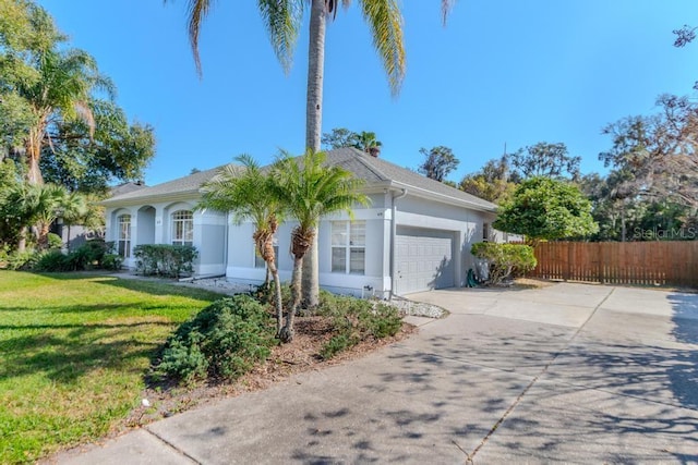 view of front of property with driveway, a front yard, fence, and stucco siding