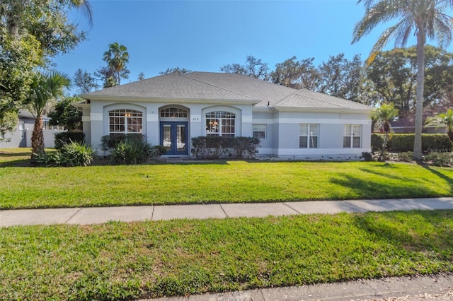 ranch-style house with stucco siding, a front yard, and french doors