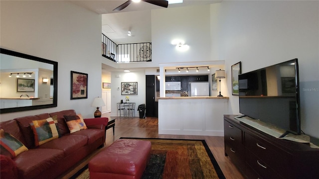 living room with a towering ceiling, wood-type flooring, and ceiling fan