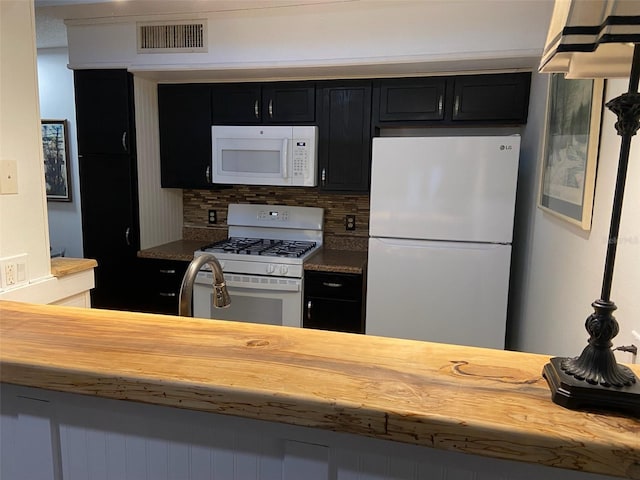 kitchen with butcher block counters, white appliances, and backsplash