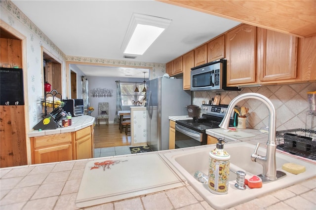 kitchen featuring stainless steel appliances, backsplash, and tile counters