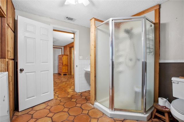 bathroom with toilet, an enclosed shower, a textured ceiling, and ceiling fan