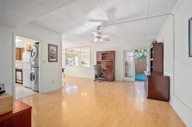 office with ceiling fan, stacked washer and clothes dryer, and light wood-type flooring