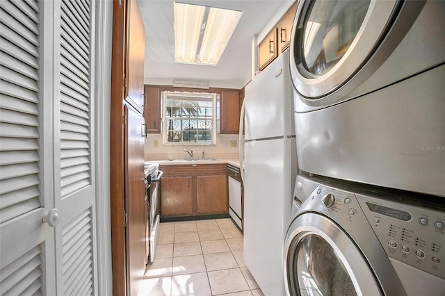 laundry room featuring sink, light tile patterned flooring, and stacked washing maching and dryer