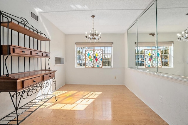 spare room with a healthy amount of sunlight, a textured ceiling, and a chandelier