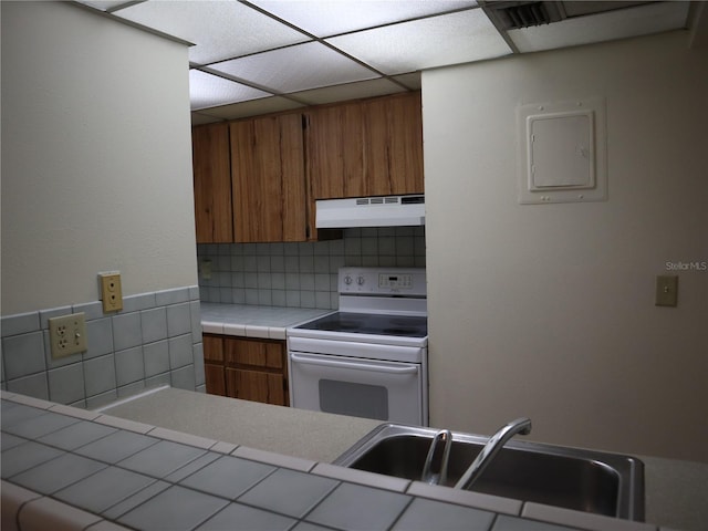 kitchen with sink, tile countertops, decorative backsplash, and electric stove