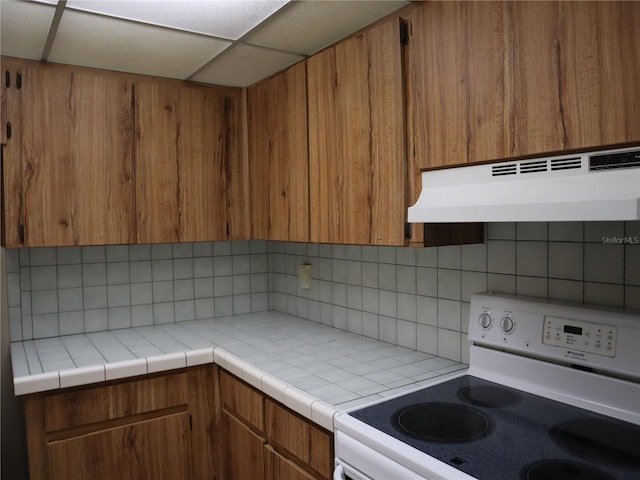 kitchen featuring tile counters, backsplash, and white electric range