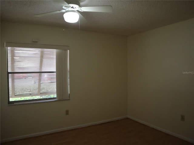 empty room with ceiling fan, wood-type flooring, and a textured ceiling