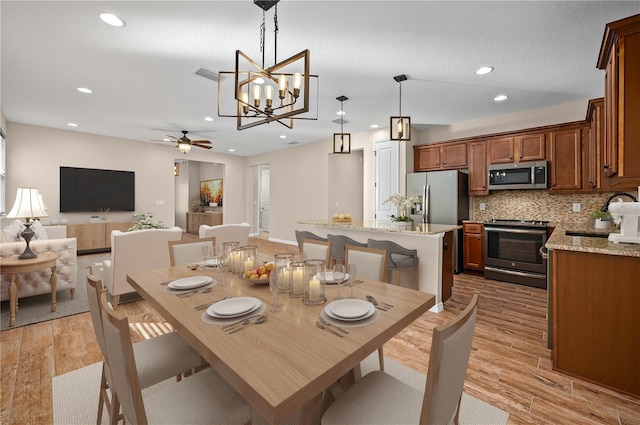 dining area featuring light hardwood / wood-style floors, sink, and ceiling fan with notable chandelier