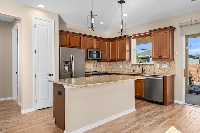 kitchen featuring decorative light fixtures, a center island, sink, appliances with stainless steel finishes, and light stone counters