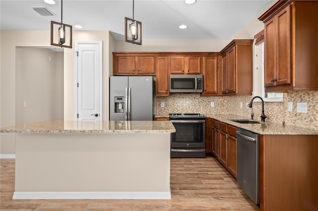 kitchen featuring appliances with stainless steel finishes, decorative light fixtures, a kitchen island, and sink