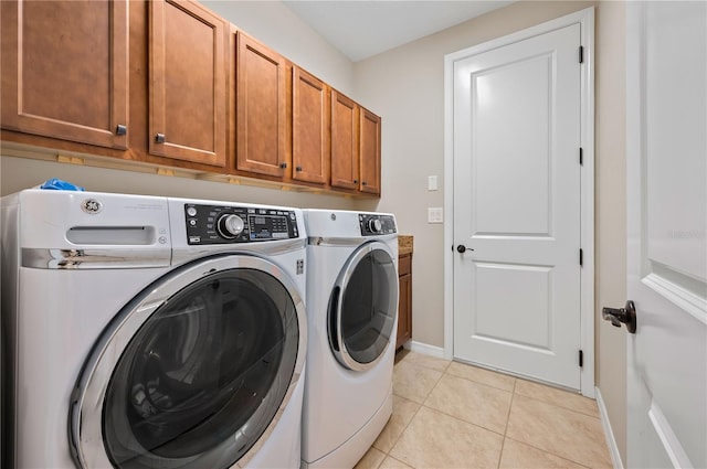 laundry room with washer and dryer, cabinets, and light tile patterned flooring