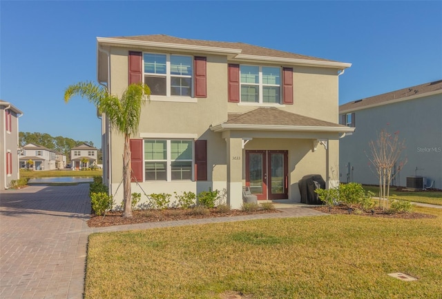 view of front of home featuring a front lawn, central AC, and french doors