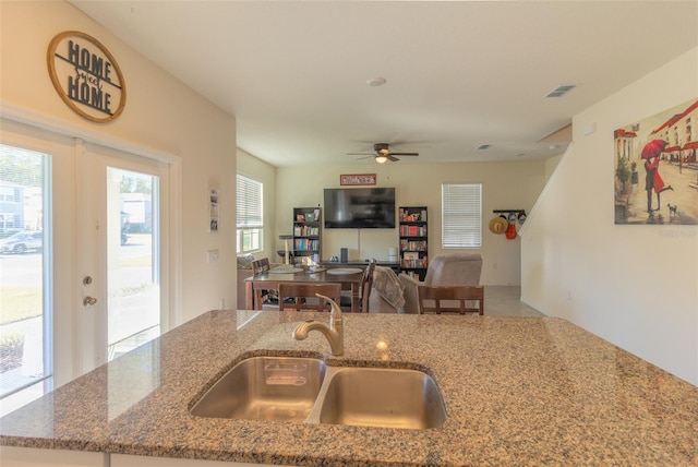 kitchen featuring ceiling fan, sink, and stone counters