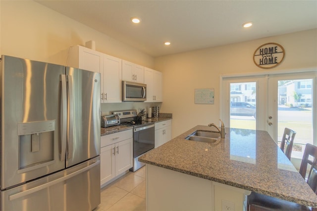 kitchen with white cabinets, sink, appliances with stainless steel finishes, and an island with sink