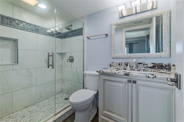 bathroom featuring walk in shower, vanity, and toilet