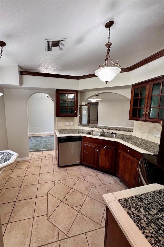 kitchen featuring backsplash, sink, stainless steel dishwasher, decorative light fixtures, and light tile patterned flooring