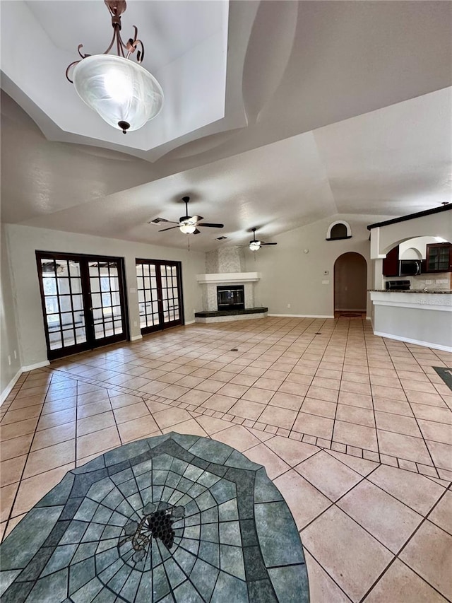 unfurnished living room featuring french doors, a raised ceiling, light tile patterned floors, and ceiling fan