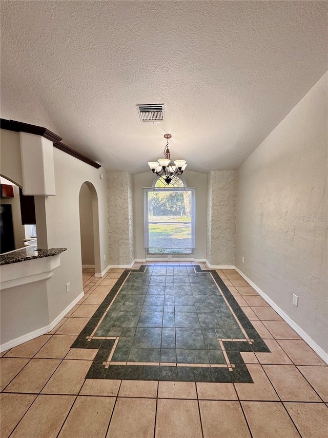 doorway to outside with tile patterned floors, a textured ceiling, and an inviting chandelier