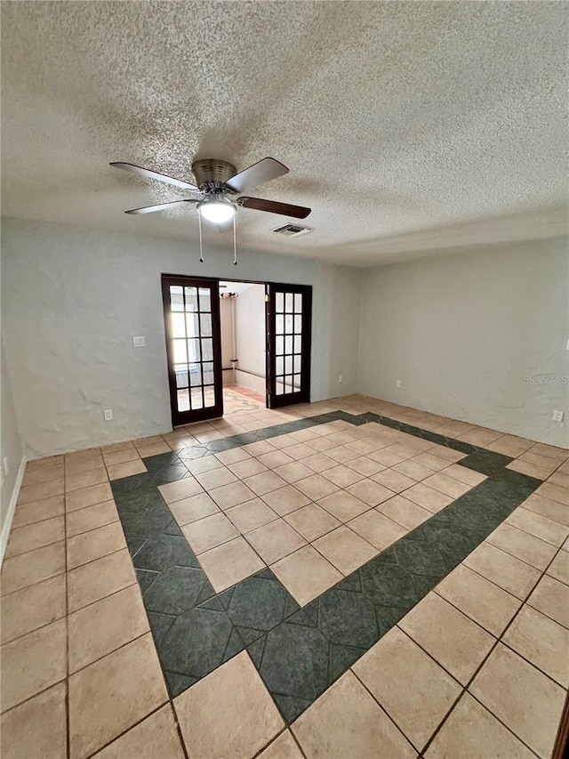 tiled empty room featuring french doors, a textured ceiling, and ceiling fan