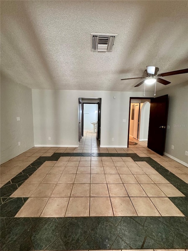 empty room featuring ceiling fan, light tile patterned flooring, and a textured ceiling